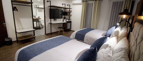 A hotel room with two beds, a desk with a computer, a TV, and a wardrobe.