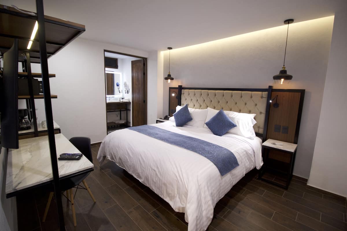 Une chambre d’hôtel comprenant un lit, des tables de chevet, un bureau avec une chaise et un miroir.