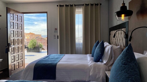 A hotel room with two beds, a view of the city, and a balcony. - Hotel Boutique Casa Loreta (Querétaro)