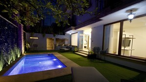 A modern outdoor pool area with a hot tub, surrounded by a well-maintained lawn and a stone wall. - Hotel Boutique Casa Loreta (Querétaro)