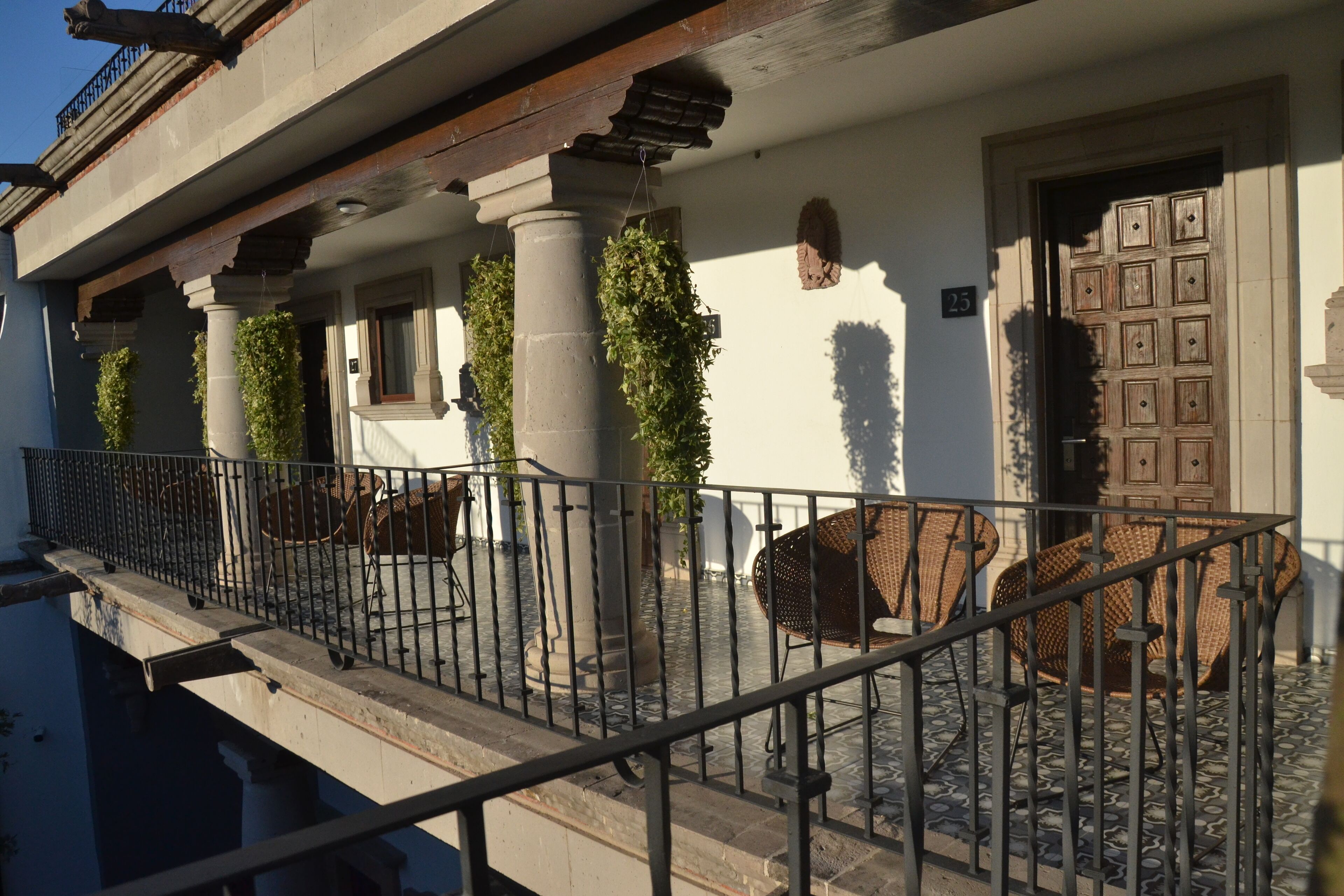 A building with a balcony, columns, and a door with a grid pattern.