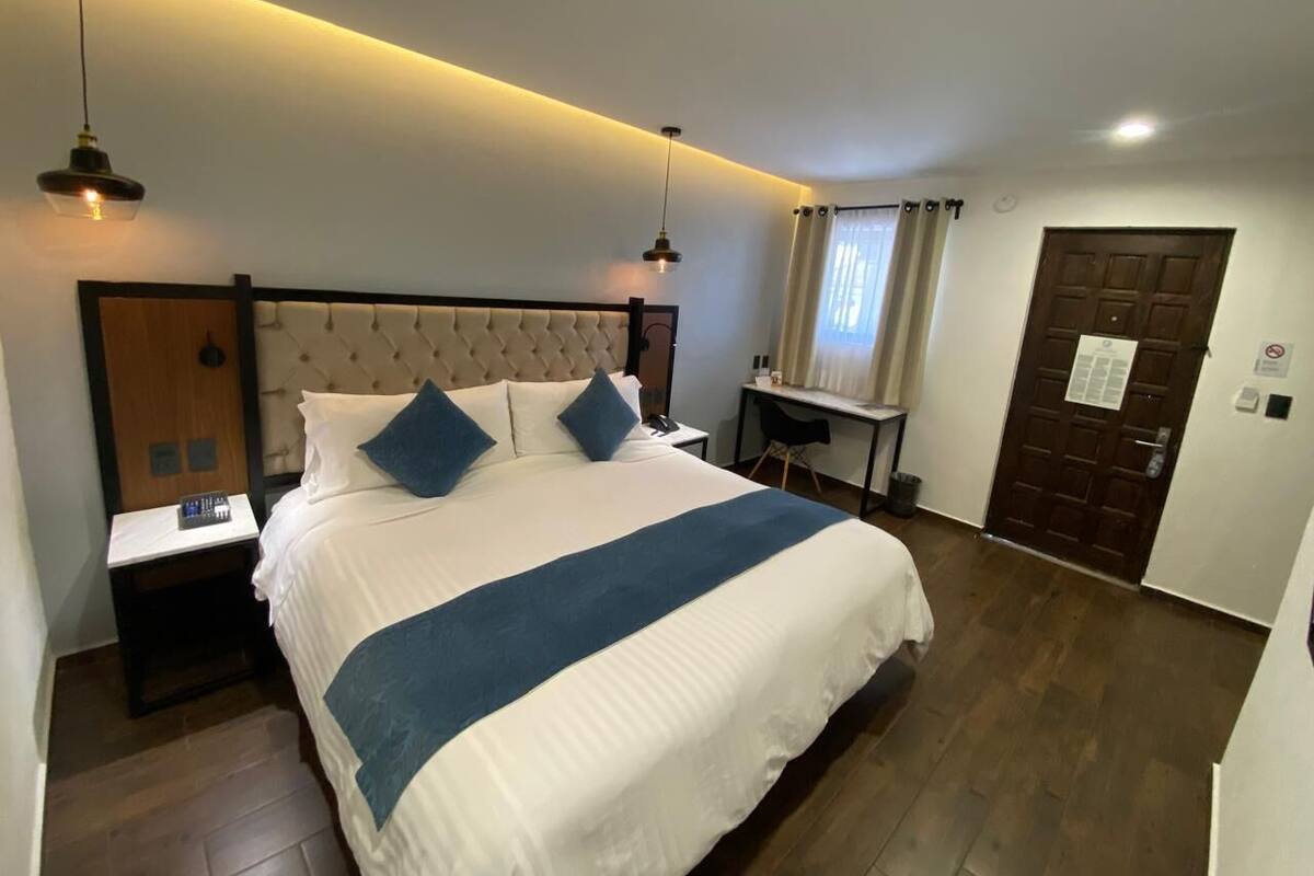 Une chambre d’hôtel avec un grand lit, des tables de chevet, un bureau et une armoire.