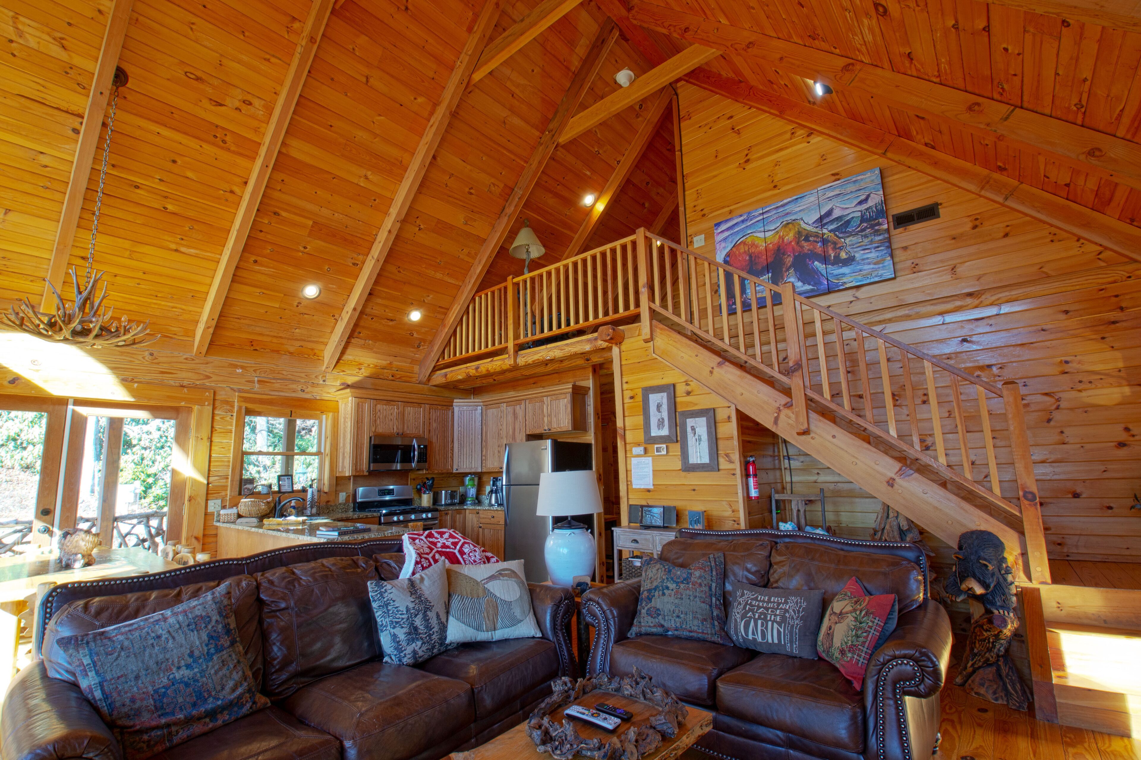 A spacious wooden cabin with a living room featuring a leather sofa and a dining area with a kitchen.