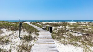 A wooden boardwalk leading to a beach with sand dunes and a clear blue sky. - Grand Pointe 610 | Amazing Views of Perdido Pass | Beachfront Condo | My Beach Getaways (Orange Beach)