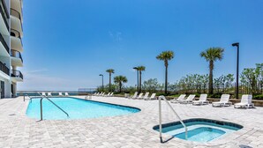 A pool area with lounge chairs and palm trees. - Grand Pointe 610 | Amazing Views of Perdido Pass | Beachfront Condo | My Beach Getaways (Orange Beach)