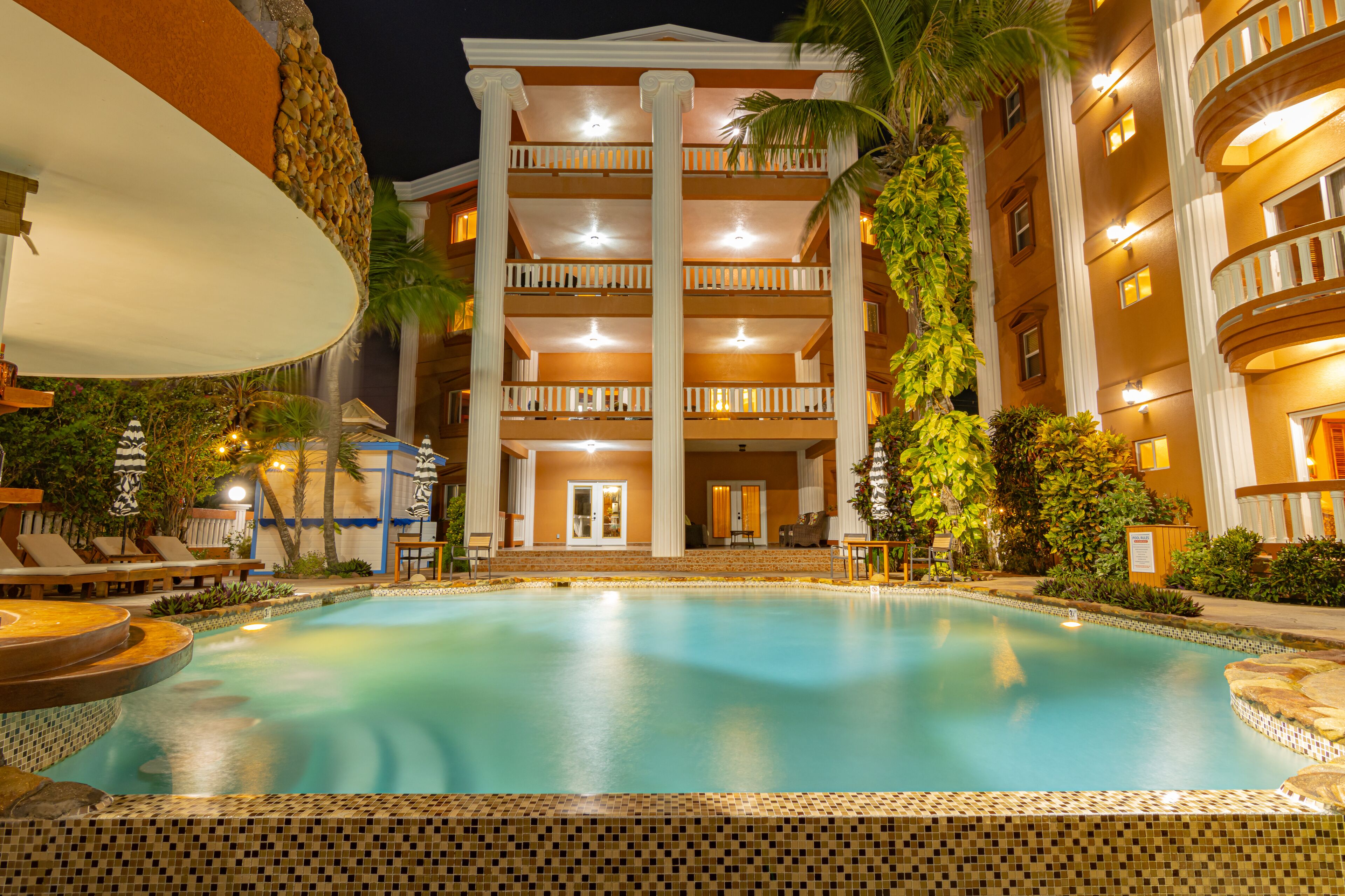 Un espace piscine d’hôtel comprenant une grande piscine, des chaises longues et un bâtiment doté de nombreux balcons.