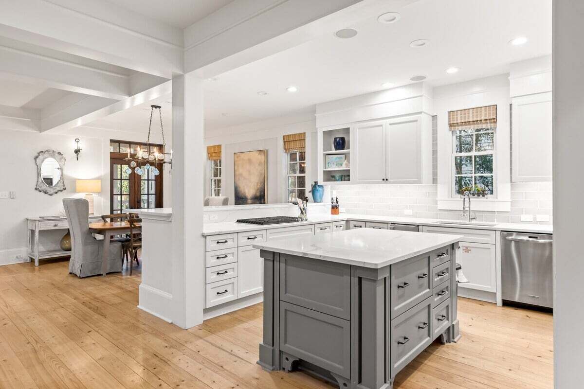A spacious kitchen with white cabinetry, a large island, and a dining area with a chandelier.