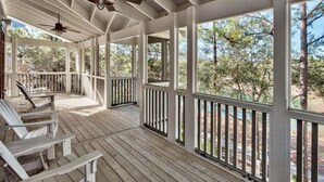 A covered porch with wooden flooring, white railings, and ceiling fans. - NEXT TO Camp WaterColor! LSV/Golf Cart, 4 Bikes, 3rd Floor Kid Zone! GORGEOUS (Santa Rosa Beach)