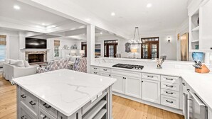 A spacious kitchen with white cabinetry, a marble countertop, and a central island. - NEXT TO Camp WaterColor! LSV/Golf Cart, 4 Bikes, 3rd Floor Kid Zone! GORGEOUS (Santa Rosa Beach)