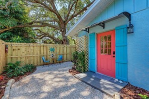A house with a red door, blue shutters, and a wooden fence.