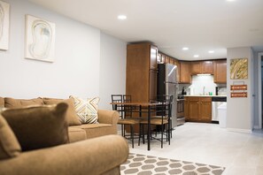 Cozy living area with a sofa, dining table, and chairs. Equipped kitchen with a refrigerator and dishwasher.