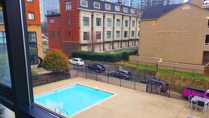 A rooftop pool with a view of surrounding buildings and parked cars.
