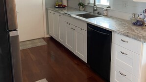 Eine moderne Küche mit weißen Schränken, einem Edelstahlkühlschrank und einem Geschirrspüler.