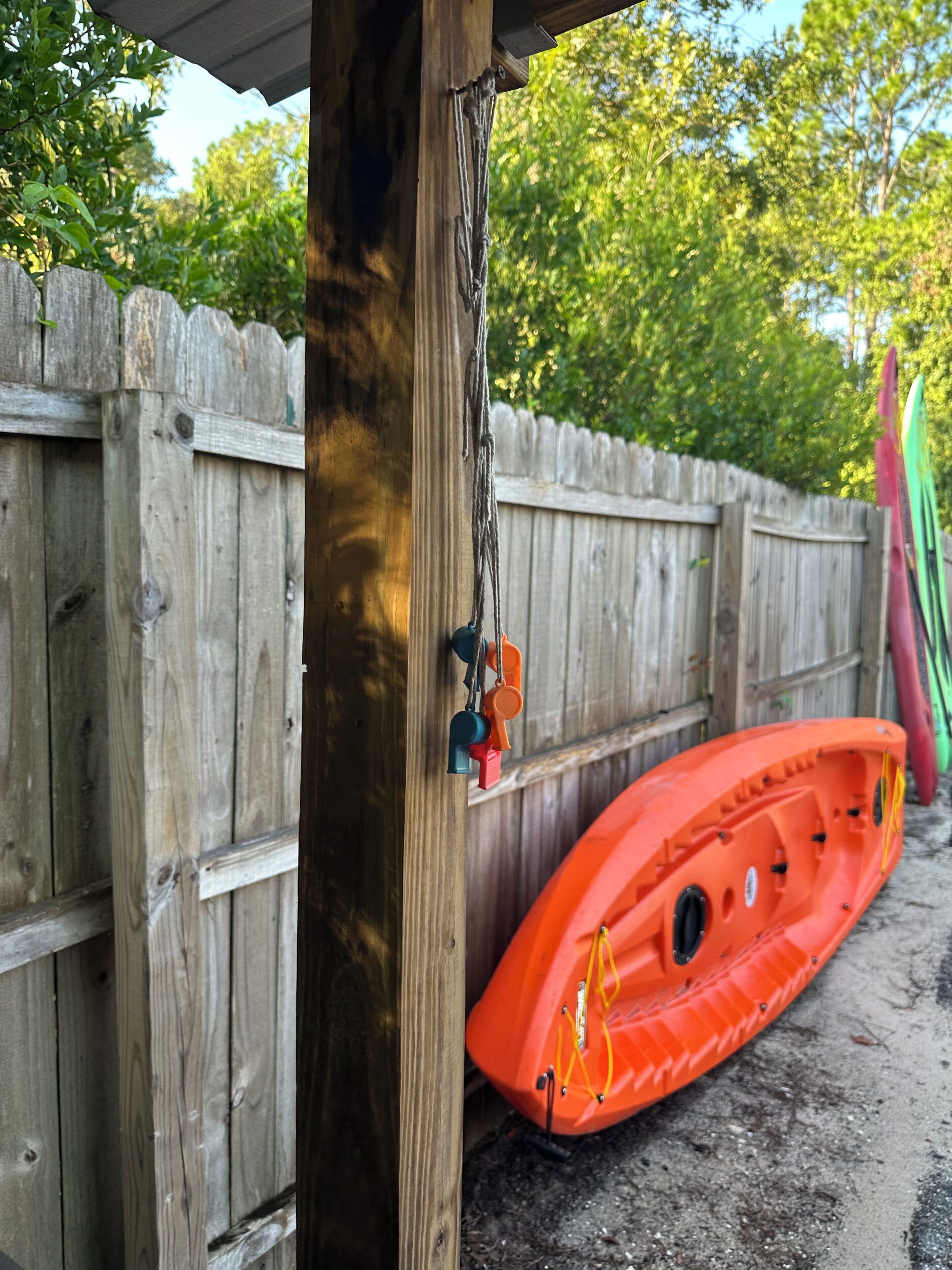 A wooden fence with a kayak and a paddle leaning against it.