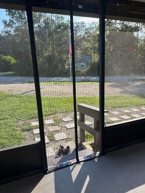 On aperçoit, à travers une porte grillagée, un espace extérieur doté d’un chemin pavé, d’un banc et d’un mât sur lequel flotte un drapeau américain.