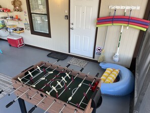 A room with a foosball table, a blue inflatable chair, a red cooler, and a 'No Pets Allowed' sign.