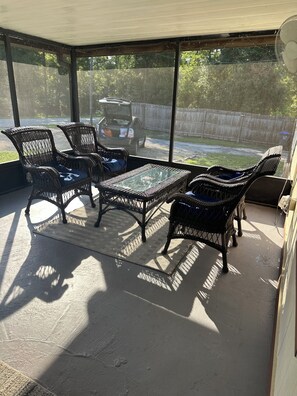 A covered patio area with wicker furniture and a glass table. - “Divers Inn” on The Rainbow River (Dunnellon)