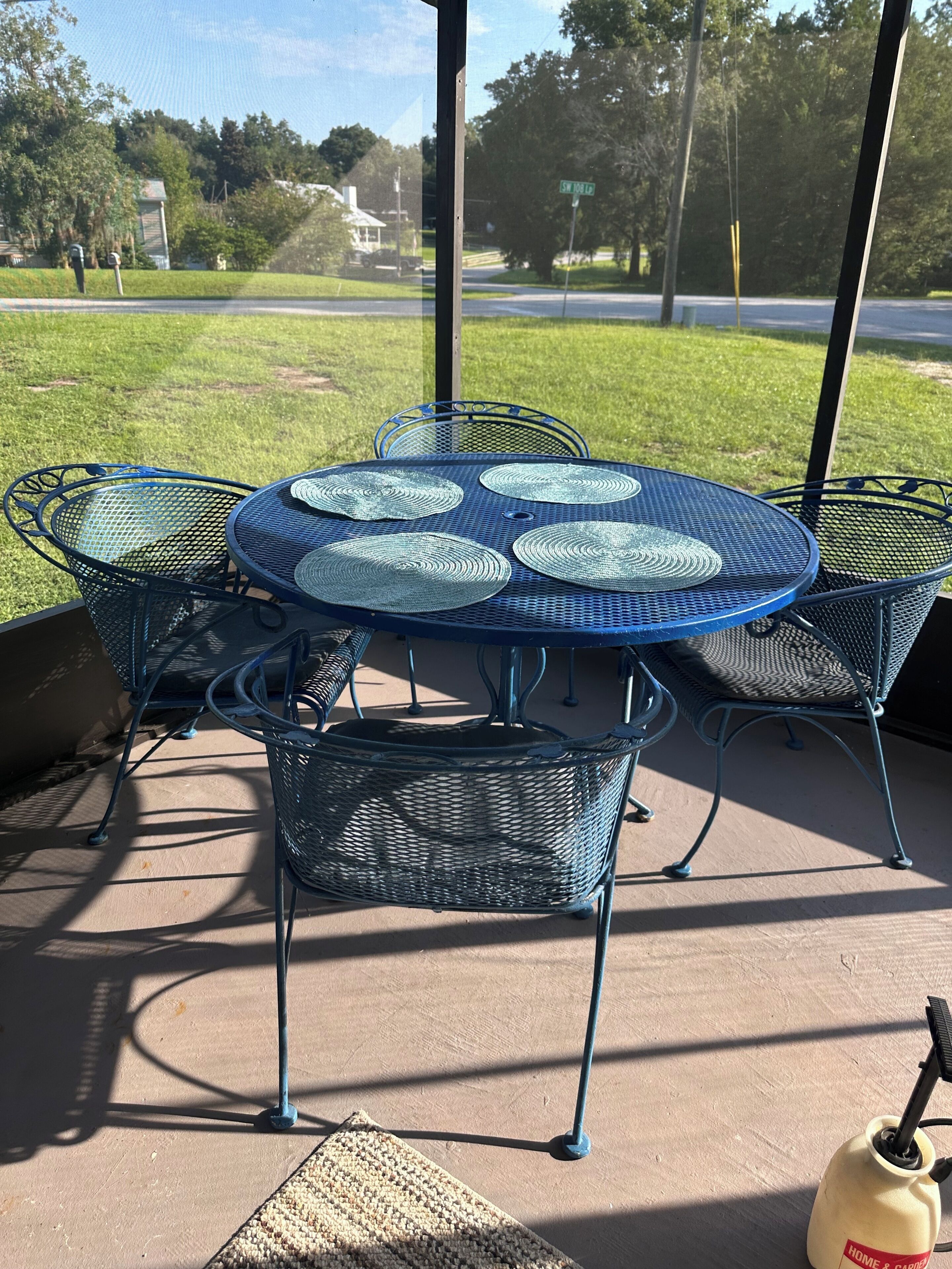 A covered patio area with a round metal table and chairs, a woven basket, and a water fountain.