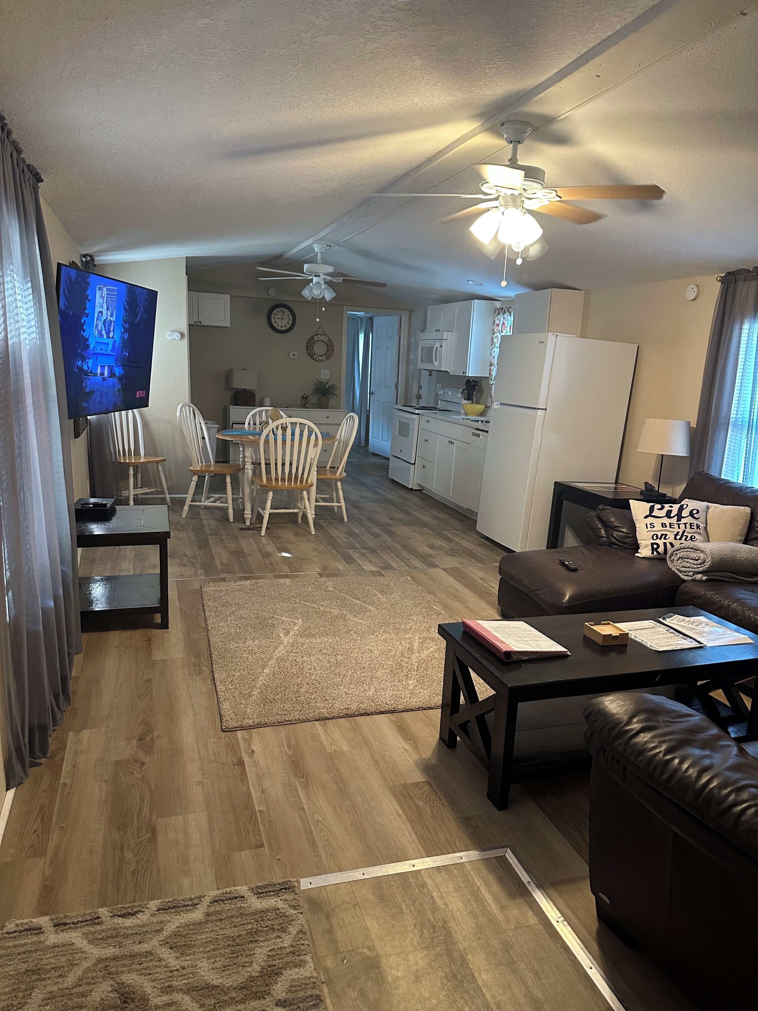 A spacious living area with a dining table, chairs, a sofa, and a television.