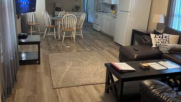 A spacious living area with a dining table, chairs, a sofa, and a television.