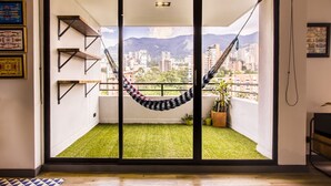 Un balcon avec un hamac, du gazon synthétique et une vue sur la ville.