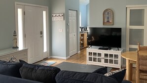 Een moderne woonkamer met een grote bank, een televisie en een eethoek.