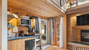 A wooden interior with a kitchen, dining area, and a fireplace. - Romantic, Peaceful Getaway; Within 10 Mi of Mt. Rushmore & Custer State Park  (Keystone)