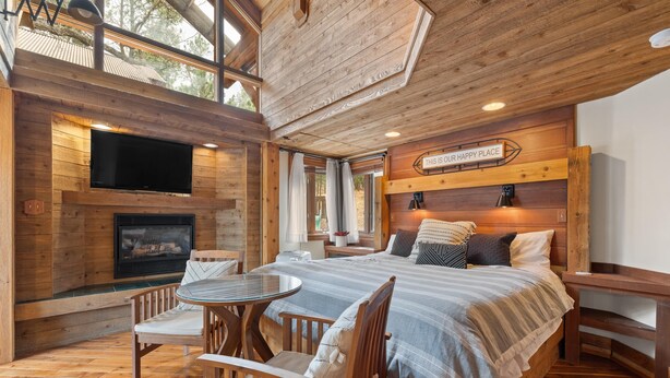A wooden interior with a bed, TV, fireplace, and dining area. - Romantic, Peaceful Getaway; Within 10 Mi of Mt. Rushmore & Custer State Park  (Keystone)