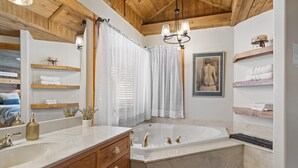 A bathroom with a double sink, a bathtub, wooden shelves with towels, a mirror, and a chandelier. - Romantic, Peaceful Getaway; Within 10 Mi of Mt. Rushmore & Custer State Park  (Keystone)