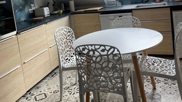 Una cocina moderna con tragaluz, sillas blancas y una mesa redonda.