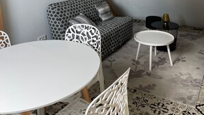 Una habitación tipo loft acogedora, con techo alto, sofá estampado, una mesa redonda blanca y una silla decorativa.