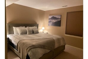 A bedroom with a bed, a nightstand, a lamp, a painting, and a window with blinds. - Winter in the mountains.   Fireplace, Game room, view. (Banner Elk)