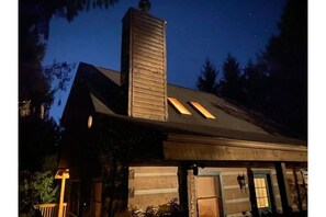 A log cabin with a prominent chimney, a porch, and a window with a number '225' on the door. - Winter in the mountains.   Fireplace, Game room, view. (Banner Elk)