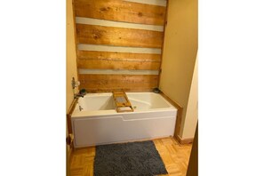 A bathroom with a wooden slat wall, a white bathtub, and a dark rug on the floor. - Winter in the mountains.   Fireplace, Game room, view. (Banner Elk)