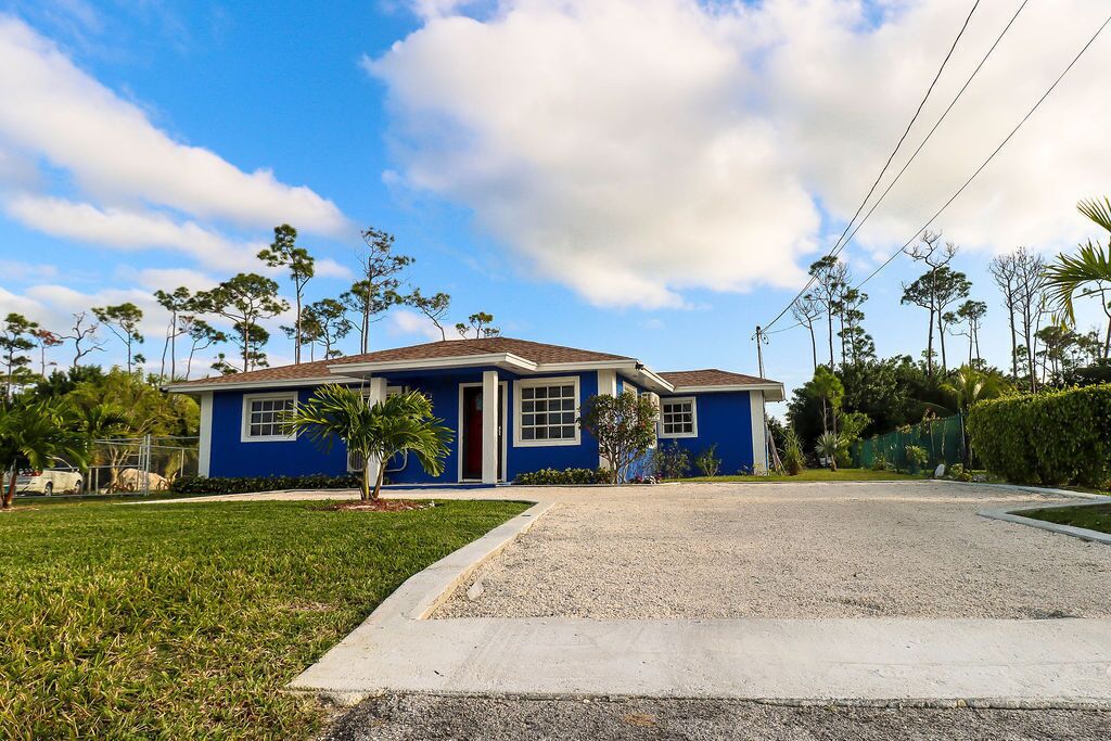 Une maison de plain-pied à l’extérieur bleu, avec une allée menant à l’entrée et une pelouse bien entretenue.