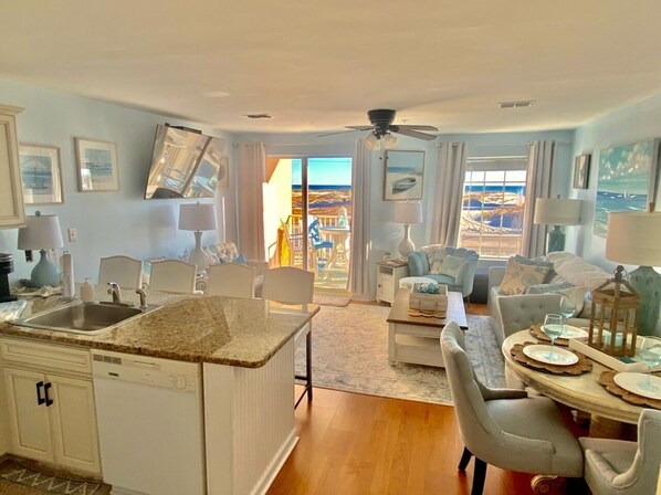 A spacious living area with a kitchen, dining table, and a view of the ocean.