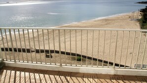 Une vue sur la plage depuis un balcon doté d’une balustrade, avec une plage de sable et la mer en toile de fond.
