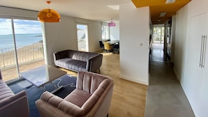 Un salon moderne avec vue sur la mer, un coin repas et une cuisine.