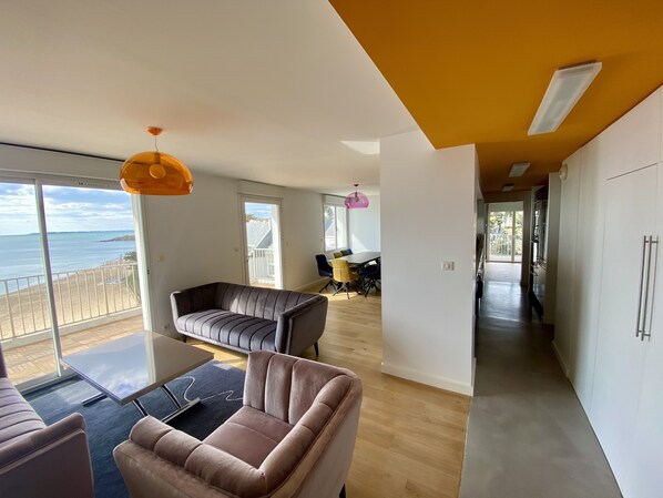 Un salon moderne avec vue sur la mer, un coin repas et une cuisine.