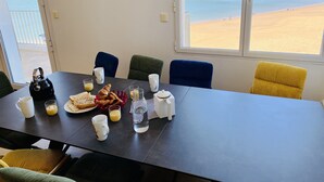 Une table à manger avec des aliments pour le petit-déjeuner, des chaises et une vue sur la plage.