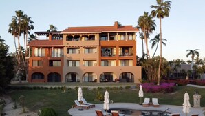 A multi-story hotel with a pool area, sun loungers, and palm trees. - Beautiful luxuries affordable, quiet ocean view one bedroom home away from away (San Jose del Cabo)
