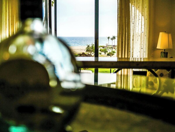 A room with a view of the ocean, a lamp on a bedside table, and a window with curtains. - Beautiful luxuries affordable, quiet ocean view one bedroom home away from away (San Jose del Cabo)