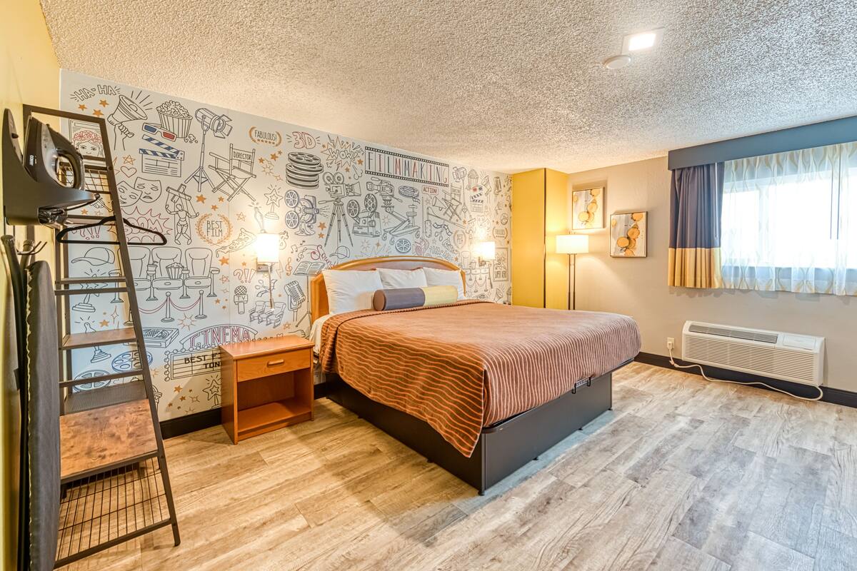 Ein Schlafzimmer mit Bett, einer Leiter, einem Schreibtisch und einer Wand mit Film-Motiven.
