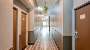A hotel hallway with doors numbered 204 and 205, a wooden floor, and a hanging floral decoration. - La Mirage Inn - Hollywood (Los Angeles)