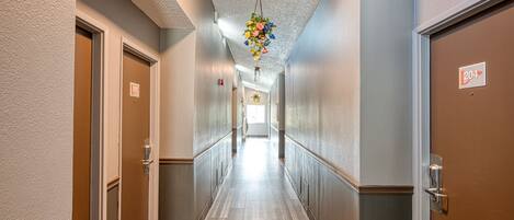 A hotel hallway with doors numbered 204 and 205, a wooden floor, and a hanging floral decoration.
