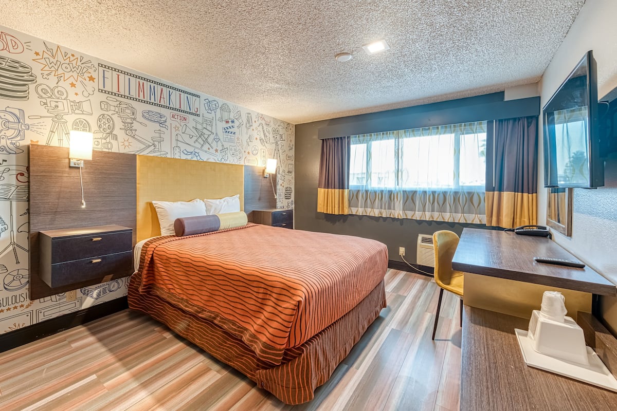 Ein Hotelzimmer mit Bett, Nachttischen, einem Schreibtisch und einem Fernseher.