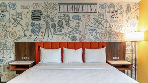A hotel room with a bed, white bedding, a red headboard, and a wall decorated with film-related doodles. - La Mirage Inn - Hollywood (Los Angeles)
