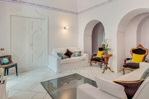 Un amplio espacio de sala con un sofá blanco, una mesa de centro de cristal y una planta decorativa.