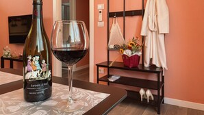 A bottle of Barbera d'Asi wine and a glass of red wine on a table with a patterned tablecloth. - WellHome   "Barbera" Apartment (ASTI)