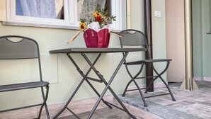 A small outdoor seating area with a table and two chairs, a vase with flowers, and a window with curtains. - WellHome   "Barbera" Apartment (ASTI)